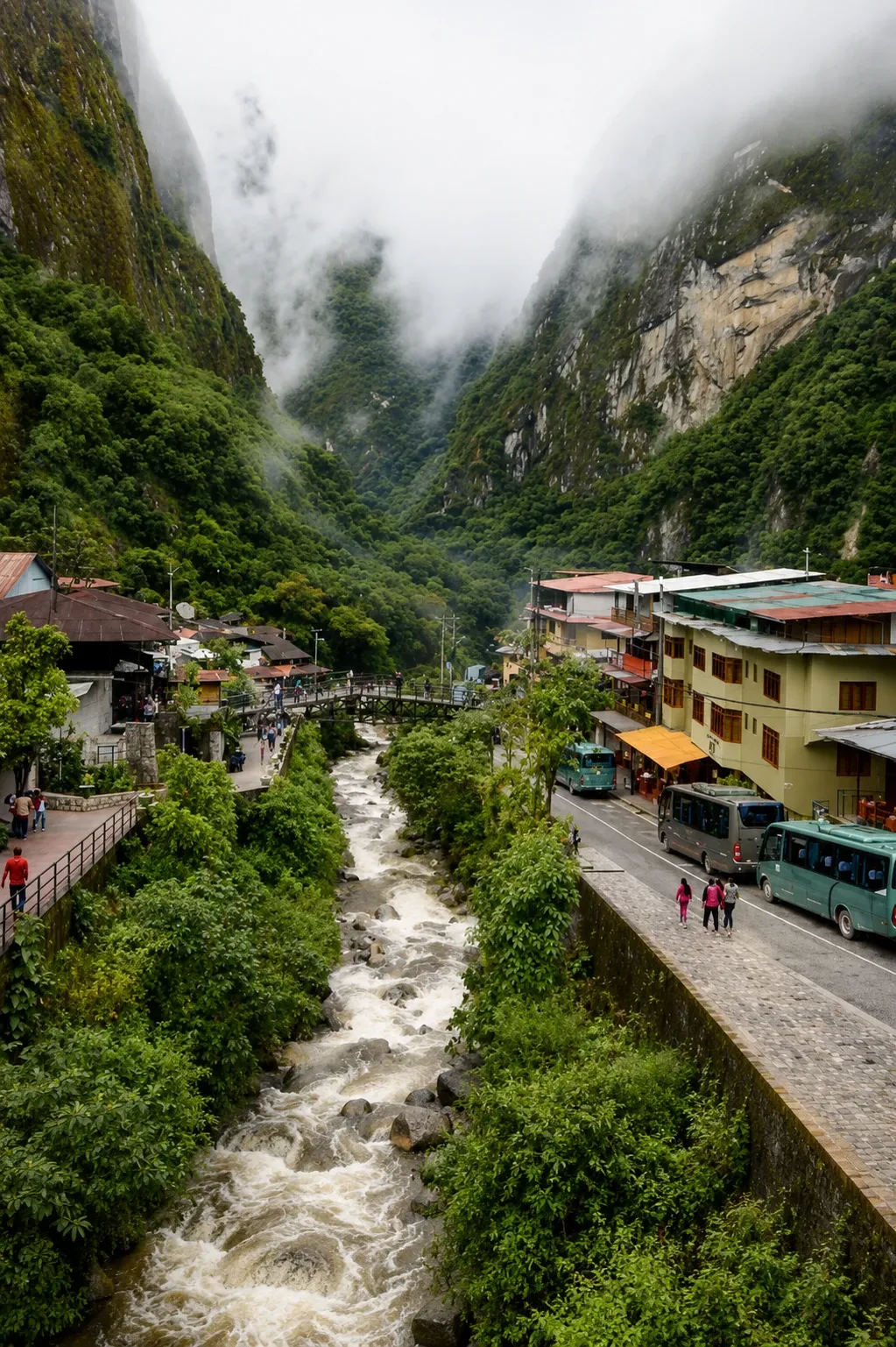 The river running through Aguas Calientes under cloud-covered cliffs