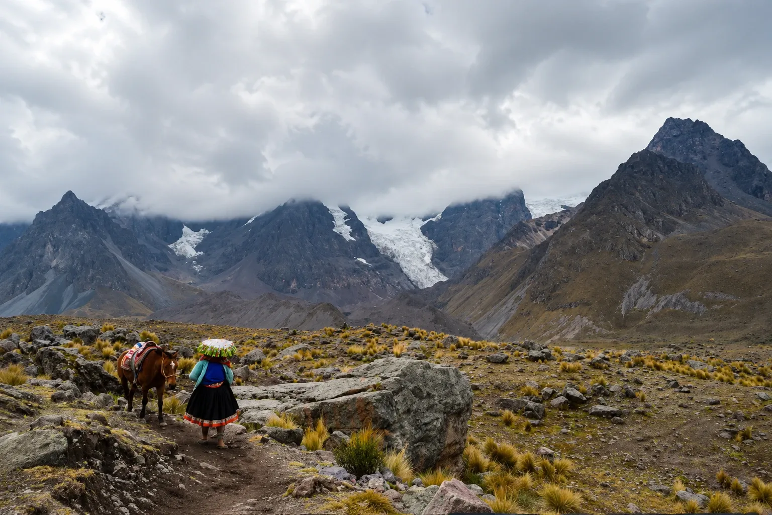 A woman leading a horse across high ground below the glaciers