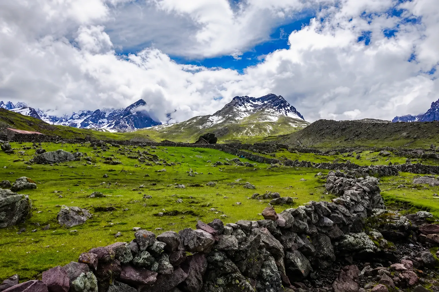 A stone-walled valley beneath the snow peaks of the Ausangate range