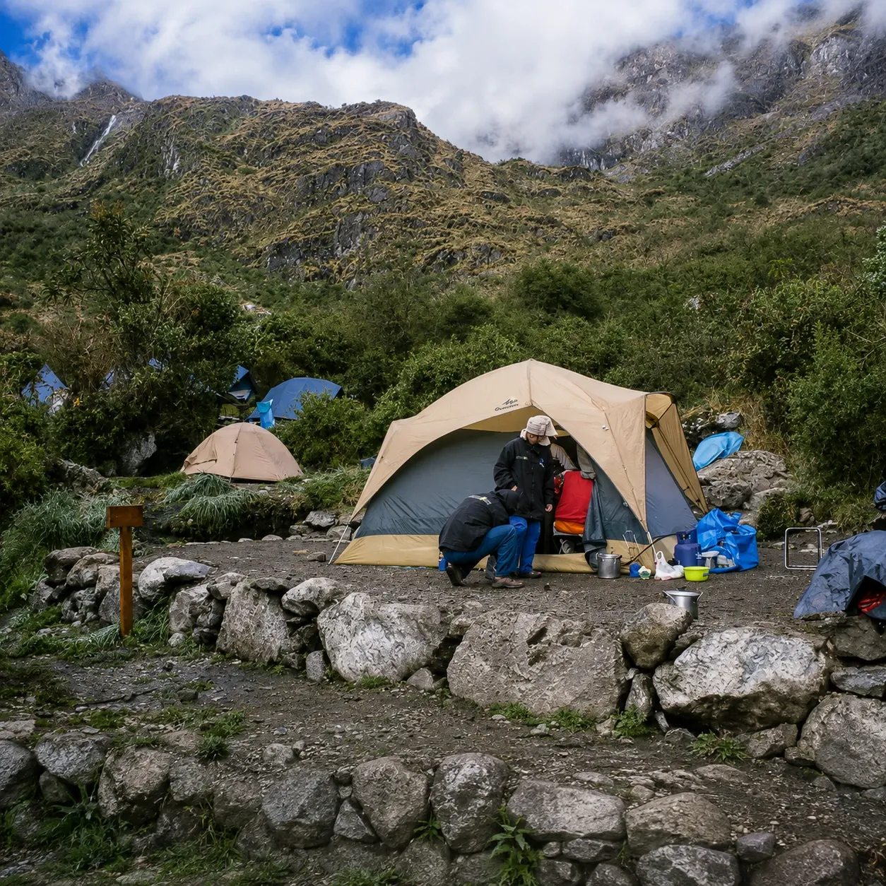 A tent pitched among stone walls beneath the mountains
