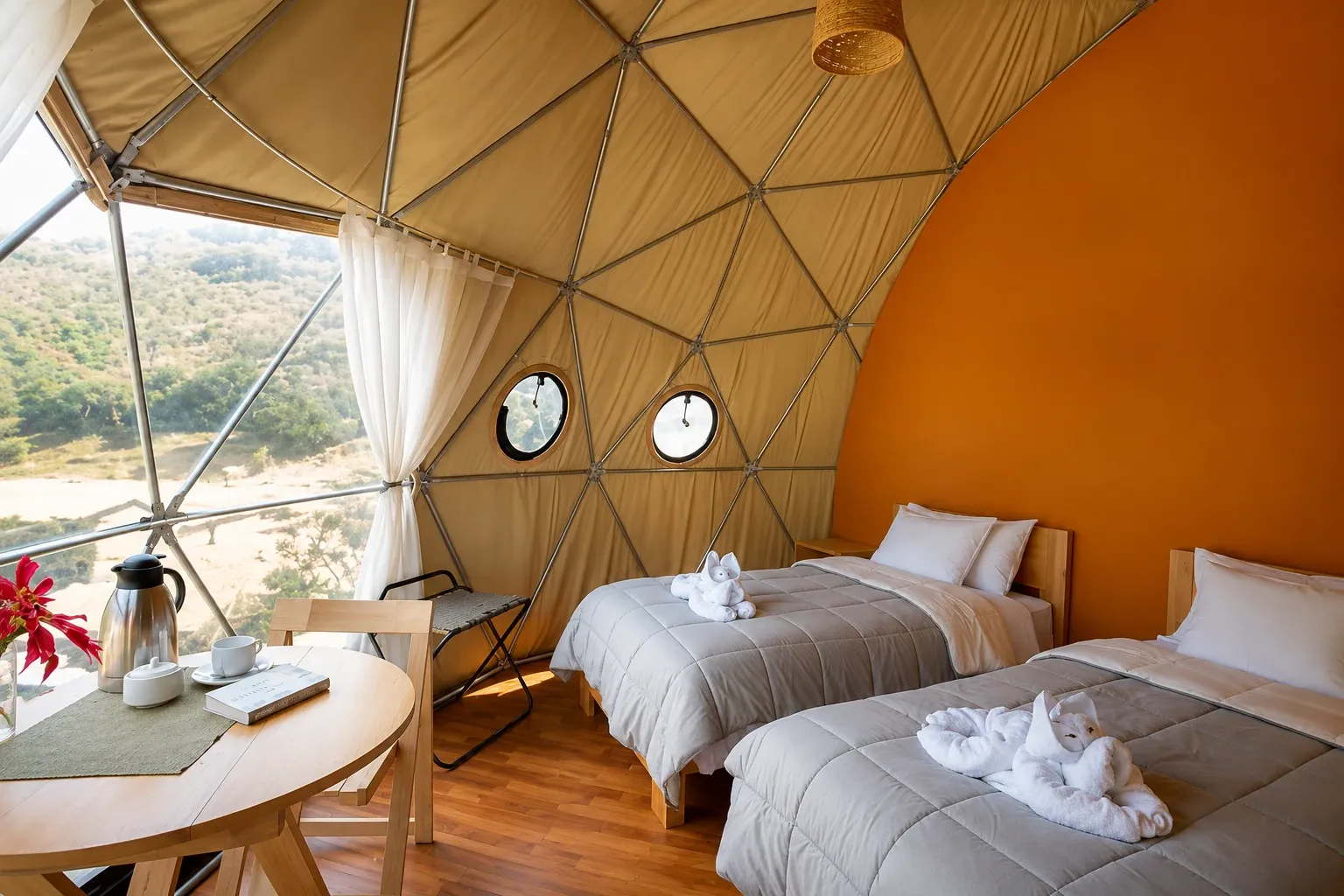 Twin beds inside a glamping dome with a window onto the valley