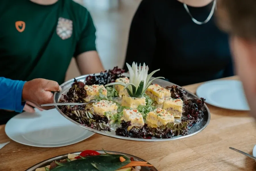 A cook serving a plated dish to walkers at lunch