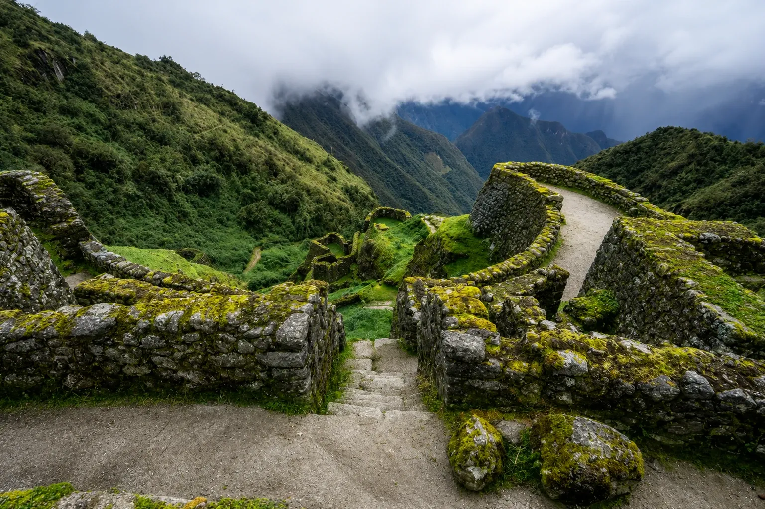 Moss-covered Inca walls beside the trail with the valley falling away