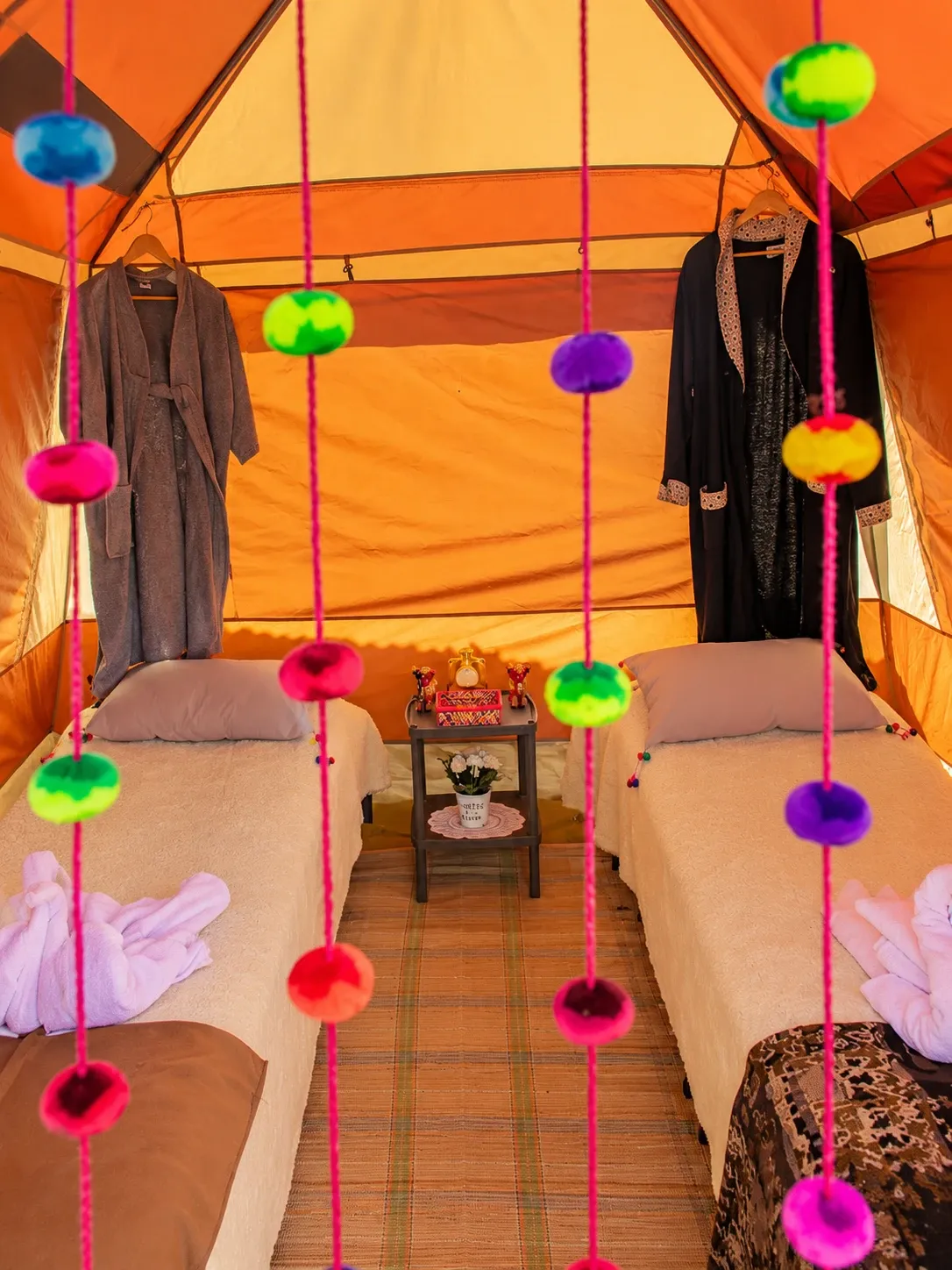 Two made-up camp beds inside a walk-in tent
