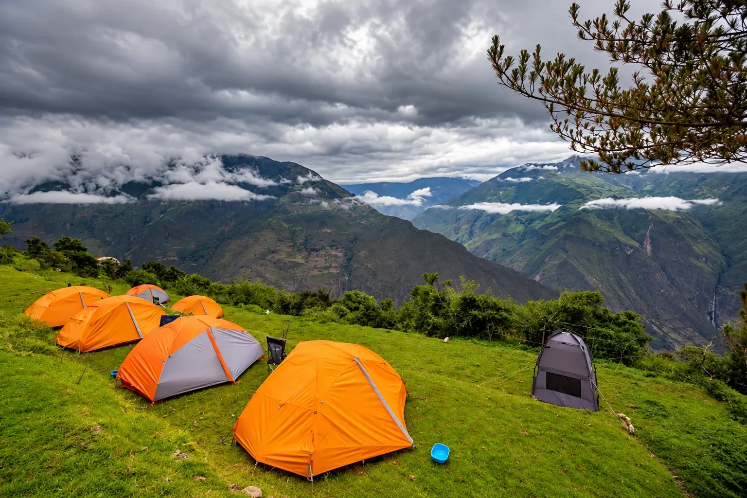 Tents on a grassy ledge looking out over the valley