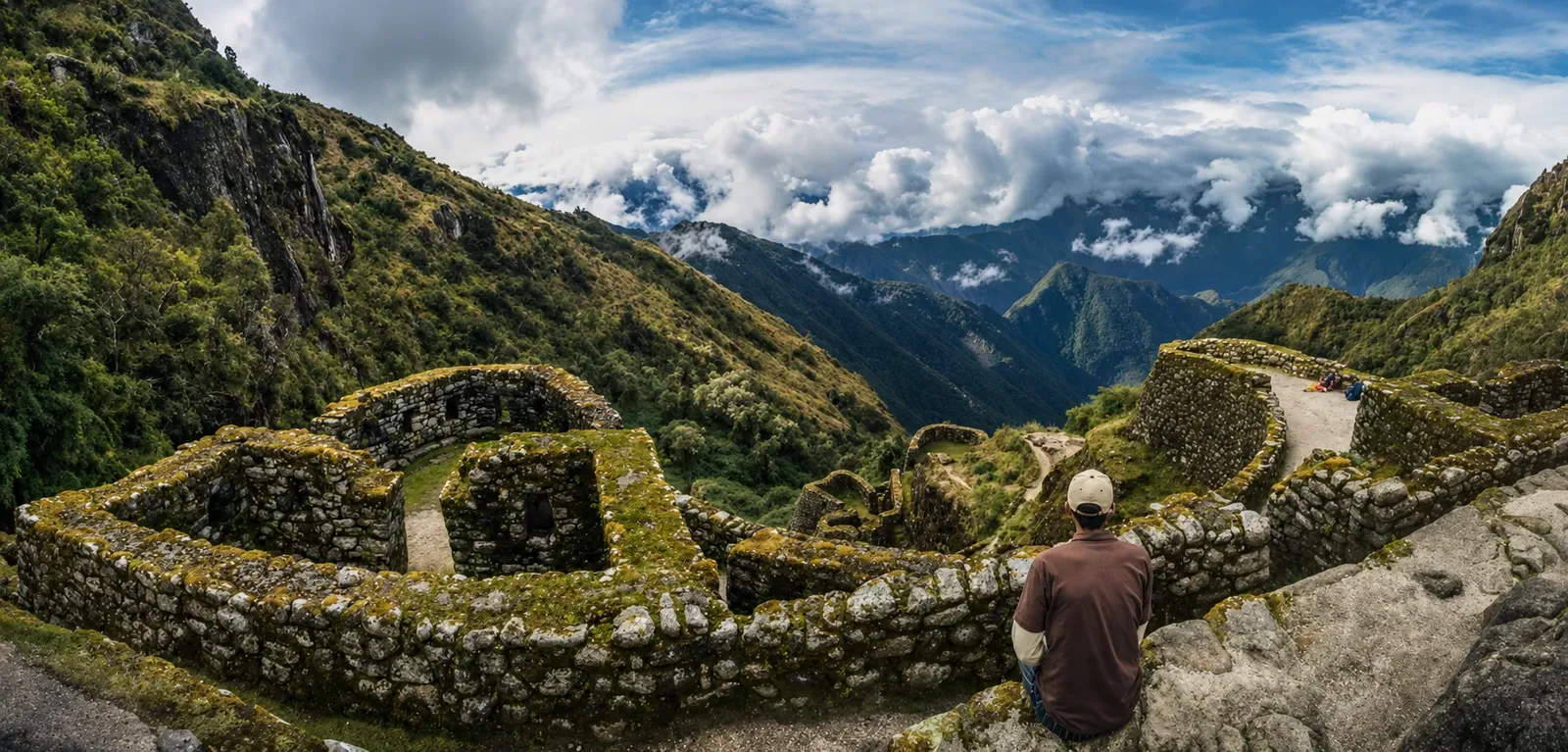A walker resting above an Inca ruin with snow peaks on the horizon