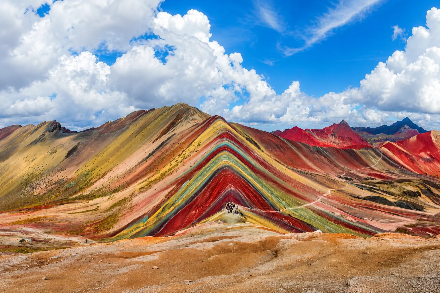 The striped mineral ridge of Vinicunca under a broken sky