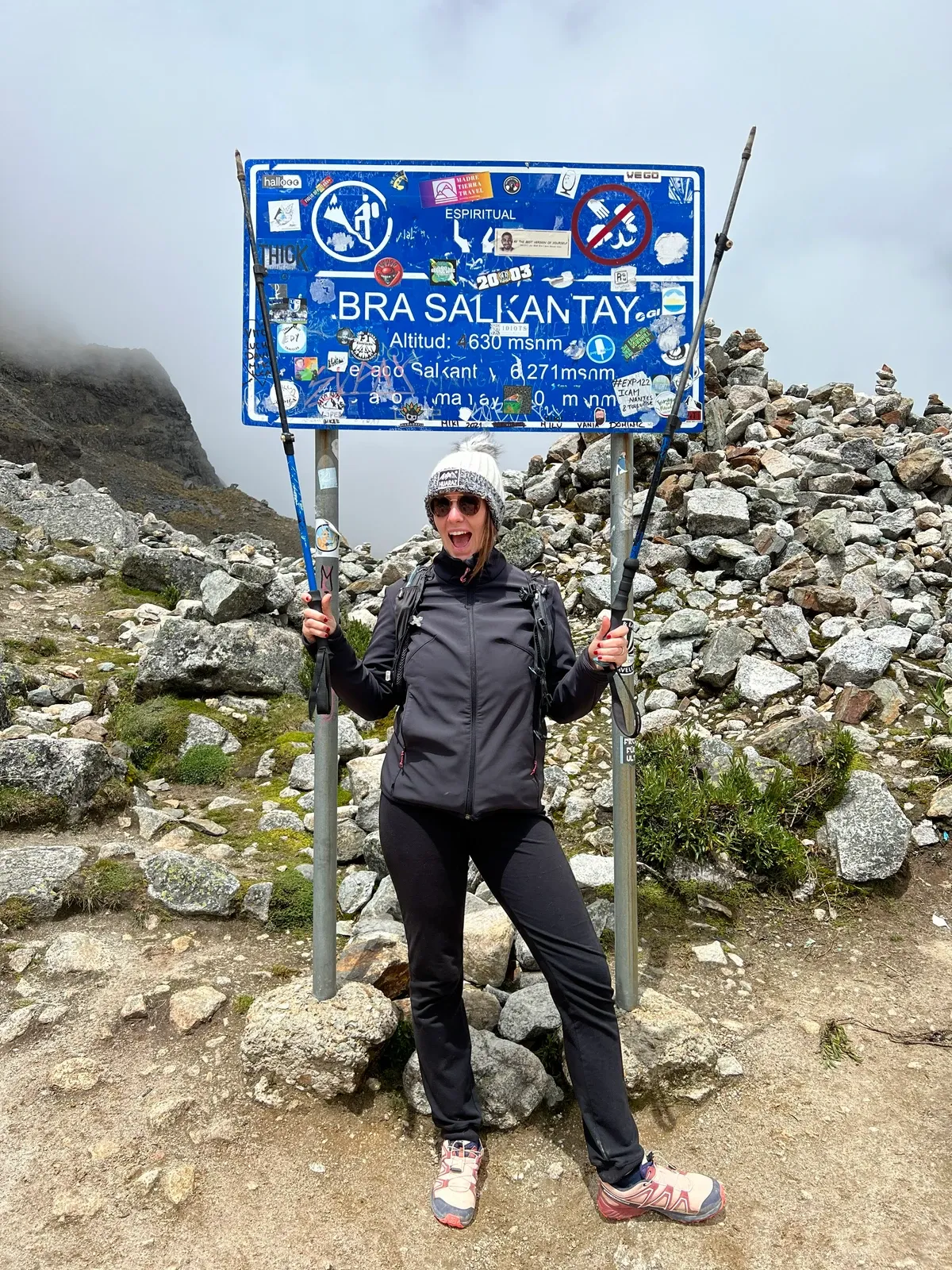 A trekker beside the sign at the top of the Salkantay Pass
