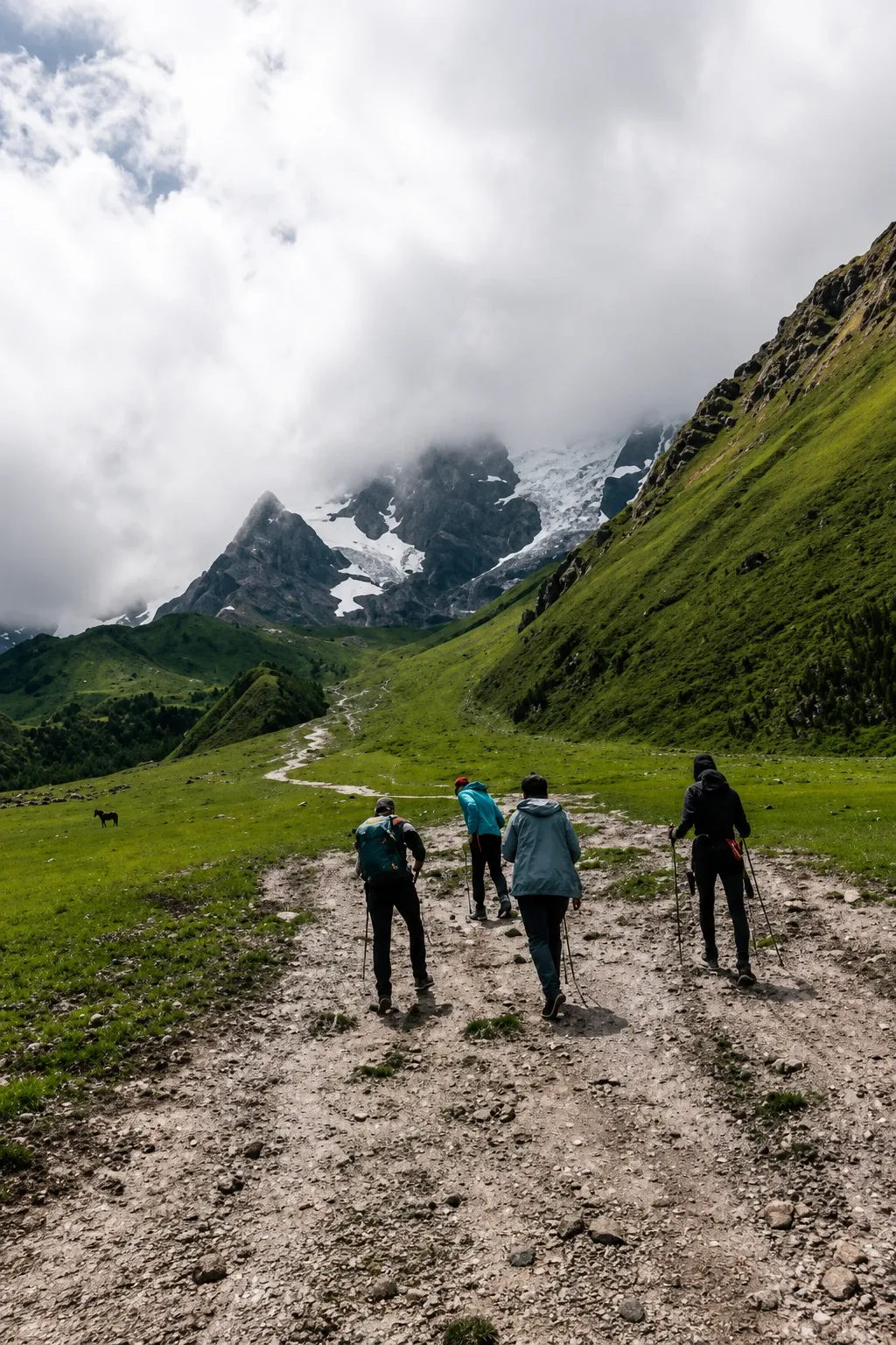 Walkers on a wide track heading up a green valley