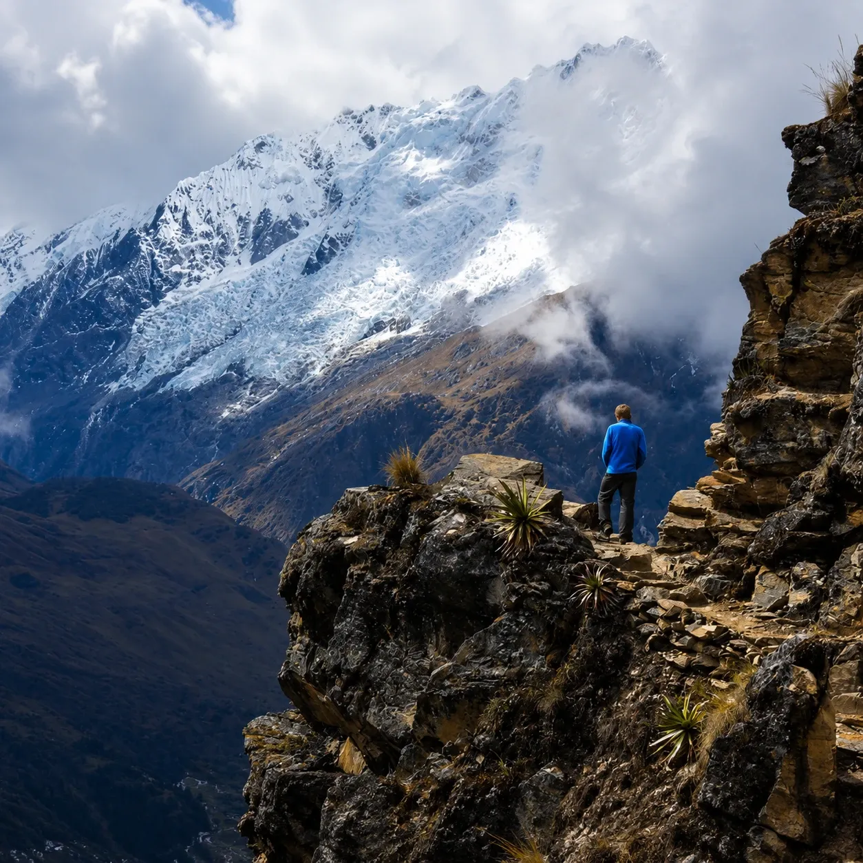 A walker on a rock outcrop facing the Salkantay glacier