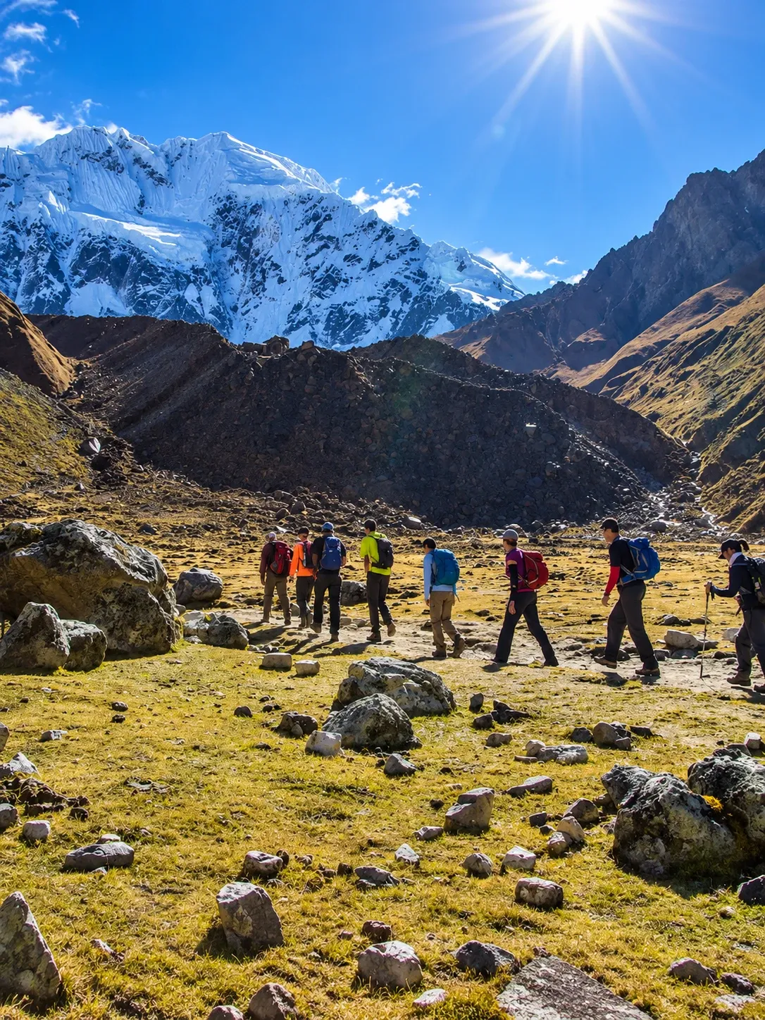 A line of walkers crossing high ground below a snow peak