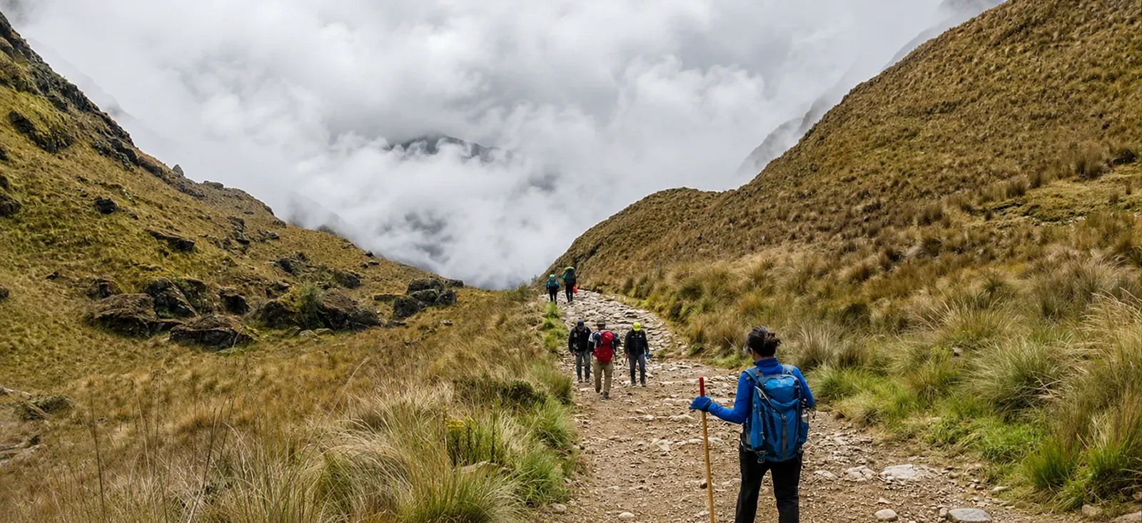Walkers following a path up a broad highland valley