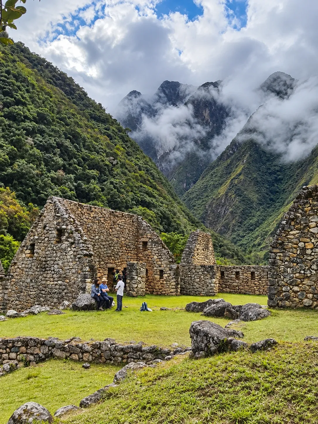 Stone houses at an Inca site in the cloud forest, peaks behind